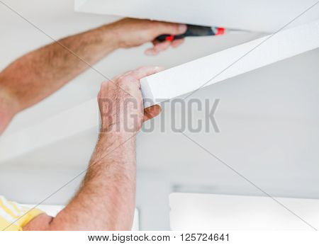 Handyman applying polyethylene foam panels to the ceiling.