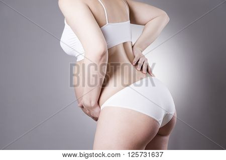 Caucasian pregnant woman in white lingerie with abdominal pain on gray studio background. Pregnancy concept