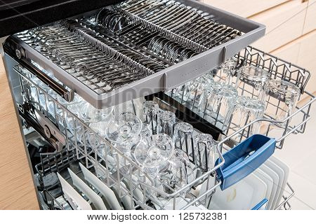 Open dishwasher with clean utensils in it.