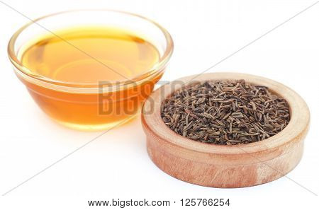Caraway seeds with essential oil in glass bowl over white background