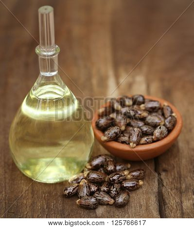 Castor oil with beans on wooden surface