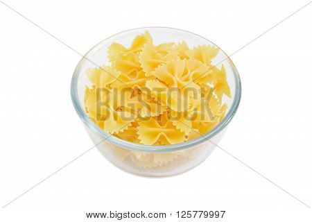 Uncooked bow-tie pasta in a transparent glass bowl on a light background