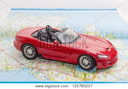 Children's red toy car cabriolet on the open road atlas