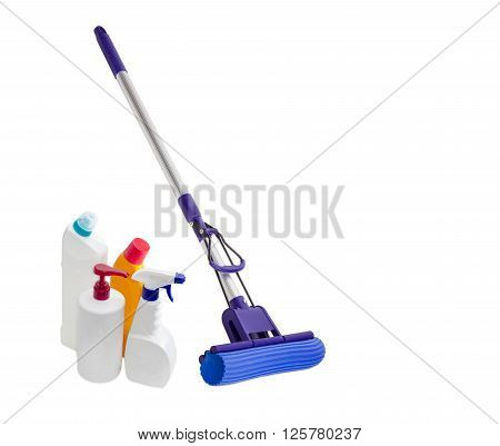 Blue plastic mop with aluminium handle mounting clamp and a sponge and several different bottles of cleaning agents on a light background