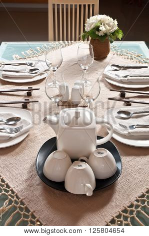 A table laid for a meal, with a white table cloth and traditional white china, table napkins, and cutlery.