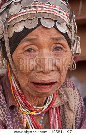 MAE SALONG,  CHIANG RAI province , THAILAND - JUN, 2004 : 
In the mountains of northern Thailand. An old woman from the Akha ethnic group. To save her money Akha women sew silver coins on headdress.