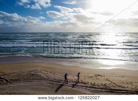 Two people walking on a beach at sunset