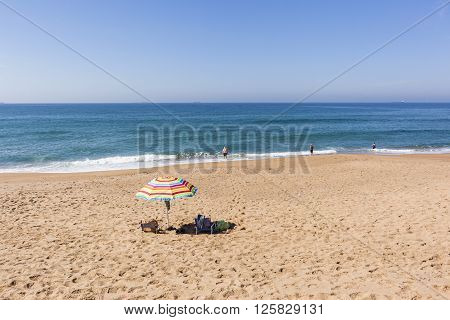 Beach blue ocean waters with holiday bathers swimming coastline landscape.