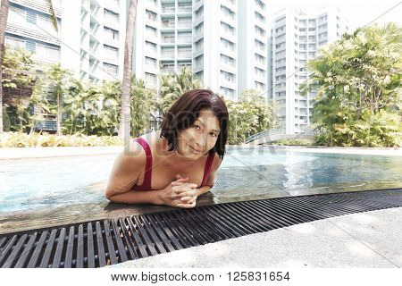 Happy healthy senior woman enjoying  swimming in the pool