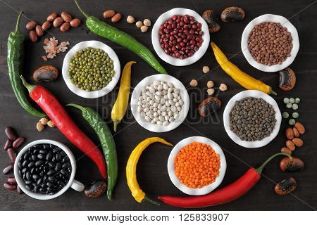 Colorful beans and lentils in ceramic bowls on a dark background.
