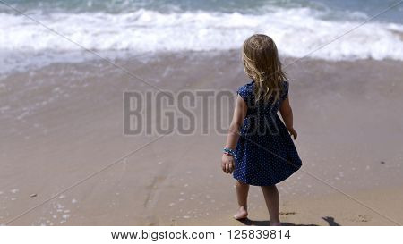 Girl in a white dress going along the sea bank