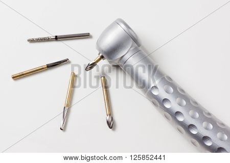 dental turbine handpiece with burs on a white background