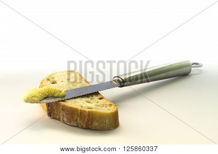 Knife on top of bread slice with butter