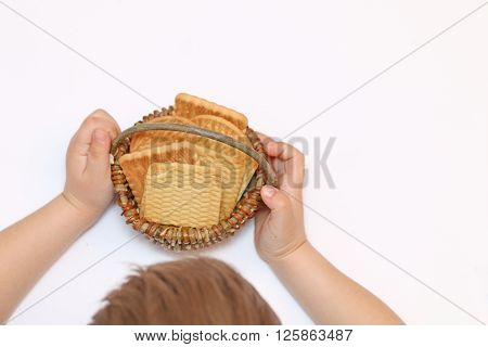 small child holds basket in hand and a basket of biscuits one of them bit of
