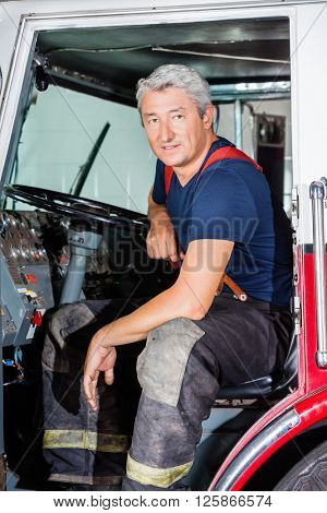 Confident Male Firefighter Sitting In Truck