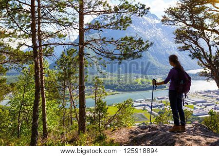 girl hiker with a backpack and trekking pole standing and looking on Romsdalsfjorden and Andalsnes Norway