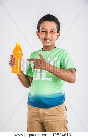 indian boy with cold drink bottle, asian boy holding cold drink bottle, small boy and cold drink, indian cute boy drinking mango juice or orange juice in plastic bottle