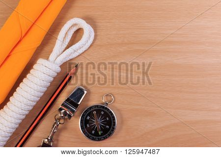 Orderliness White Scout Rope, Scarf, Whistle, Pencil And Compass On Wooden Table.