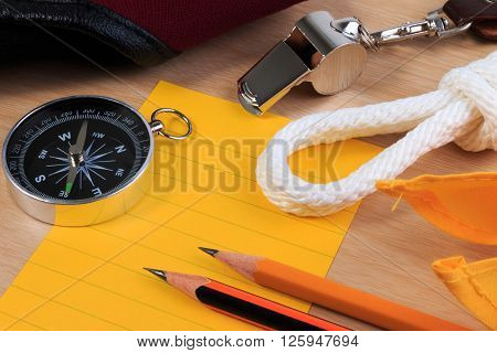 Orderliness White Scout Rope, Scarf, Whistle, Compass, Pencil And Paper Note On Wooden Table.