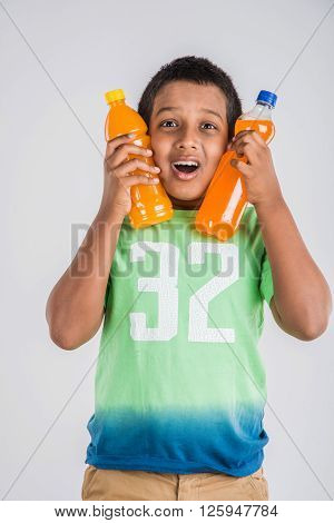 indian boy with cold drink bottle, asian boy holding cold drink bottle, small boy and cold drink, indian cute boy drinking mango juice or orange juice in plastic bottle