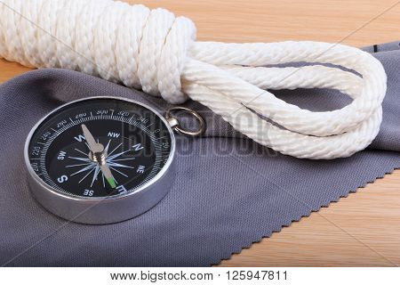 Orderliness White Scout Rope, Compass And Fabric On Wooden Table.