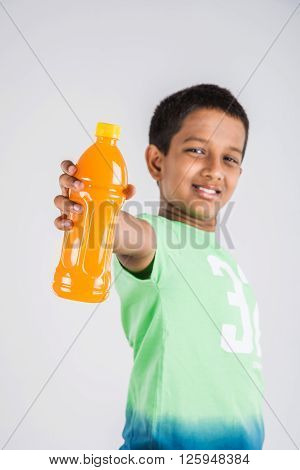 indian boy with cold drink bottle, asian boy holding cold drink bottle, small boy and cold drink, indian cute boy drinking mango juice or orange juice in plastic bottle