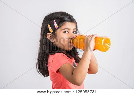 indian girl with cold drink bottle, asian girl drinking cold drink in pet bottle, girl kid and cold drink, indian cute girl with mango or orange cold drink in plastic bottle, isolated