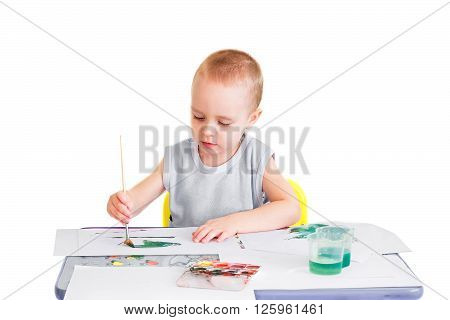 Little boy makes his first drawings in watercolor. Isolated on a white background.