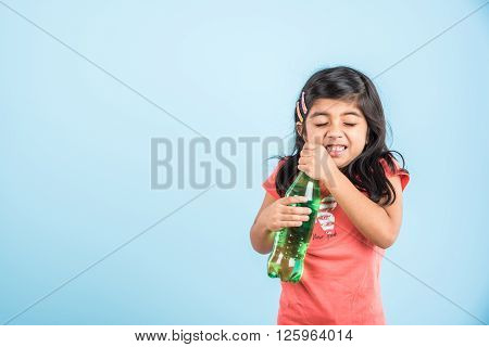 indian girl with cold drink bottle, asian girl drinking cold drink in pet bottle, girl kid and cold drink, indian cute girl with lemon or carbonated cold drink in plastic bottle, isolated on blue
