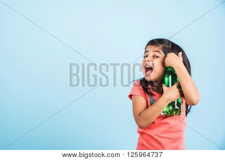 indian girl with cold drink bottle, asian girl drinking cold drink in pet bottle, girl kid and cold drink, indian cute girl with lemon or carbonated cold drink in plastic bottle, isolated on blue