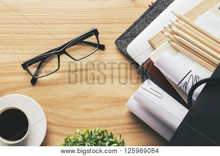 Topview of wooden desk with glasses coffee pencils and other items