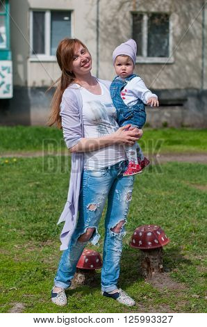 a young mother holds a daughter outdoor