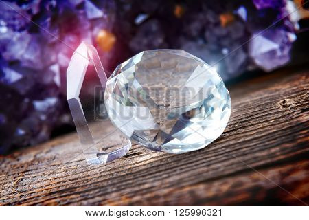 Clear colorless rhinestones on wooden board with amethyst geode in background