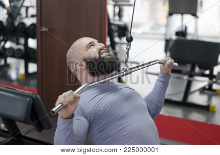Purposeful young man enjoying healthy lifestyle, training hard at fitness center