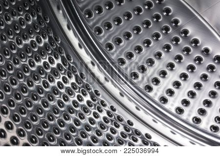 Steel shiny with holes the surface of the washing machine drum inside