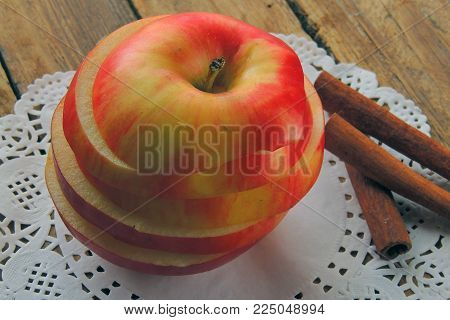 Fresh ripe red apples and cinnamon sticks on wooden background.