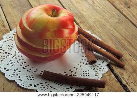 Fresh ripe red apples and cinnamon sticks on wooden background.