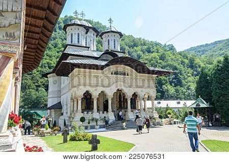VALEA JIULUI, ROMANIA - AUGUST 1, 2017: Tourists visit the old Lainici Monastery on a summer's day, detail from the courtyard with exterior paintings