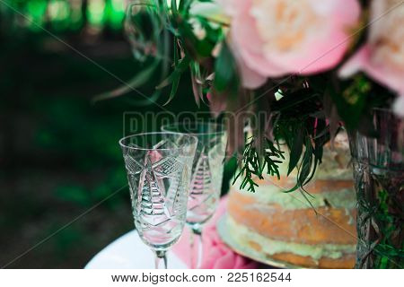 two glasses on the table on the background of flowers and cake. wedding ceremony in the open air