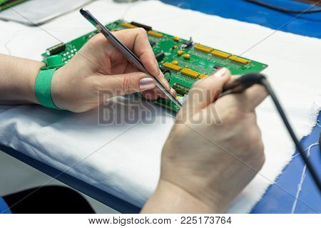 The process of assembling an electronic module. The worker's hands place electronic components on the printed circuit board. Workplace assembly plant electronics industry