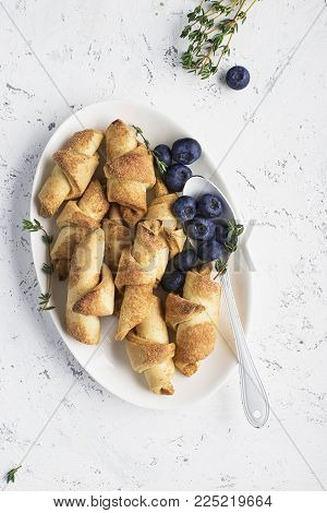 Homemade fresh cookies dusted powdered sugar in white plate with fresh blueberries