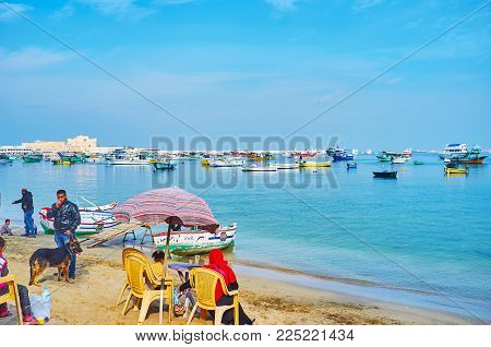 Alexandria, Egypt - December 17, 2017:  People Relax On The Sand Shore Of Eastern Harbor With A View