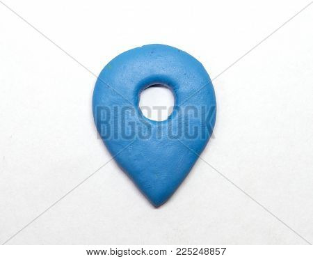 Modelling clay navigation sign on white background. Blue pointer isolated. Navigation pointer in naive nursery style. Children hobby modeling. Handmade point mark. Road map navigation route symbol