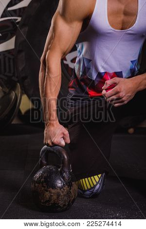 Strong and muscel man's hand with a kettle-bell. 