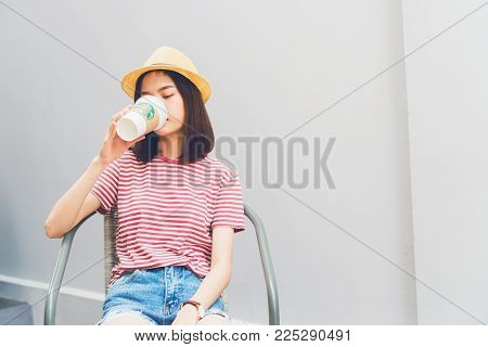 Bangkok, Thailand - February 06, 2018 : Woman drinking Starbucks coffee on the chair, Starbucks brand is one of the leaders in coffee service worldwide.