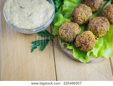Bowl With Tahina Sauce And Falafels On A Salad Sheet On A Wooden Table. Eastern Vegetarian Meal Of C