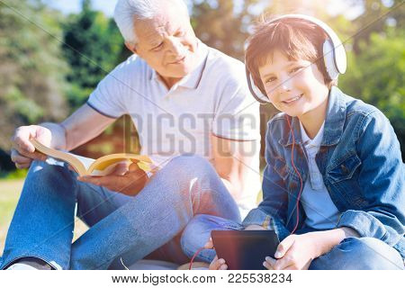 Love My Granddaddy. Selective Focus On A Happy Boy Wearing Headphones Looking Into The Camera With A
