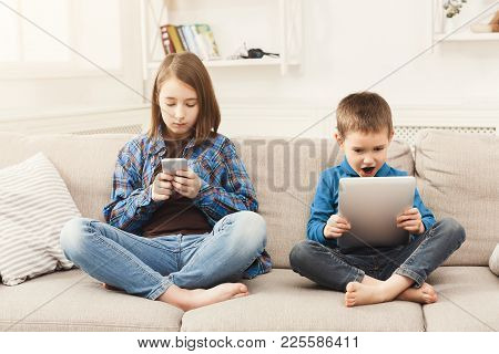 Two Kids With Gadgets. Sister And Brother Surfing The Net Or Playing Online Games On Smartphone And 