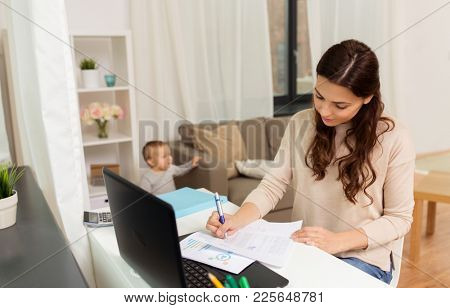motherhood, multi-tasking, family and people concept - happy mother with baby, papers and laptop working at home
