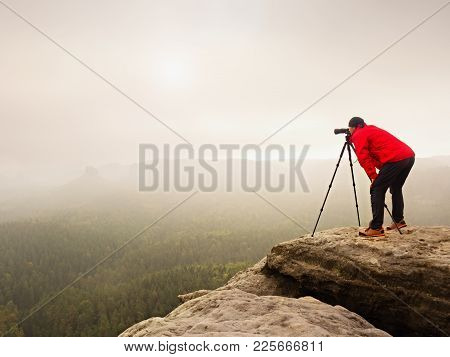 Hiker With Camera On Tripod Takes Picture From Rocky Summit. Alone Photographer At Edge Photograph M